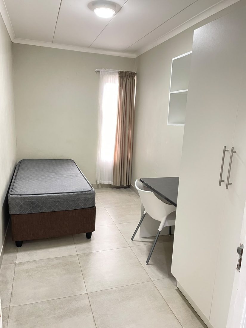 Furnished single room at K1 Rentals — bed, study desk and built-in cupboard